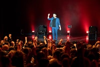 a man on stage with his hands raised in the air