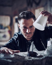 a man is holding a cup and looking at it