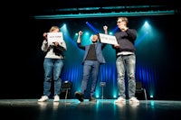 three people standing on stage holding signs