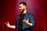 a man in a blue jacket is speaking on stage