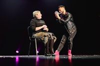 a man on stage with a woman on a chair