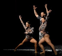 three dancers on stage with their arms outstretched