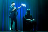 a magician on stage with a woman in front of him