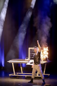 a magician on stage with smoke coming out of his mouth